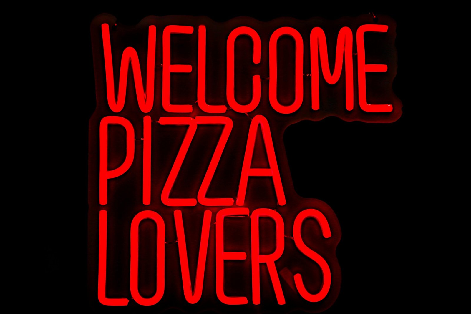 Bright red neon sign welcoming pizza lovers, perfect for restaurant decor.